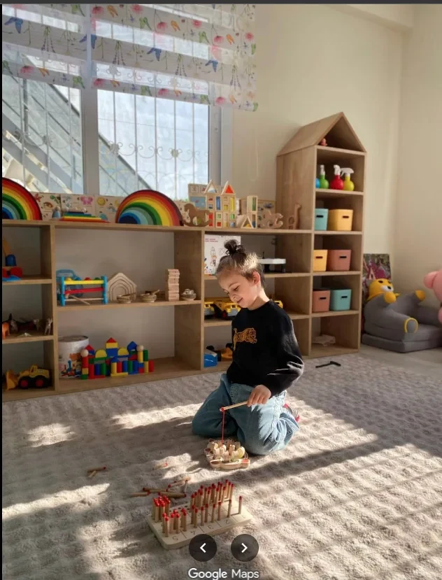 Halıda ahşap oyun materyaliyle bir öğrencimiz — montessori esintili oyun
